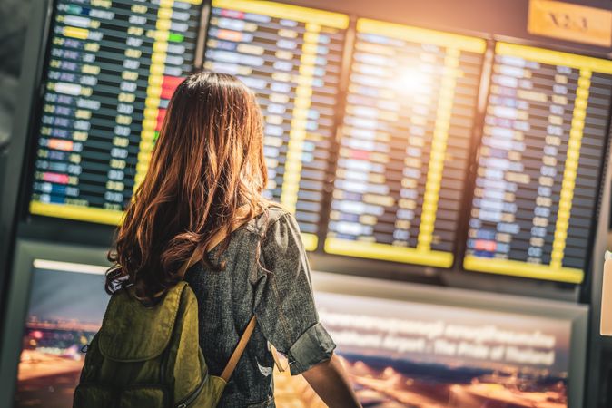 Female traveler standing in  airport looking at departures board