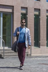 Young businessman walking next to office buildings while holding a shoulder bag outdoors