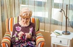 Mature woman knitting a wool quilt with patches