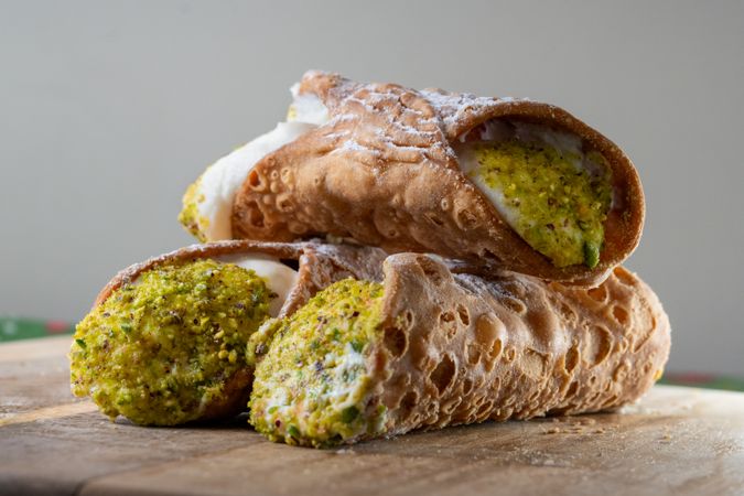 Stack of Sicilian cannoli filled with ricotta and crushed pistachios