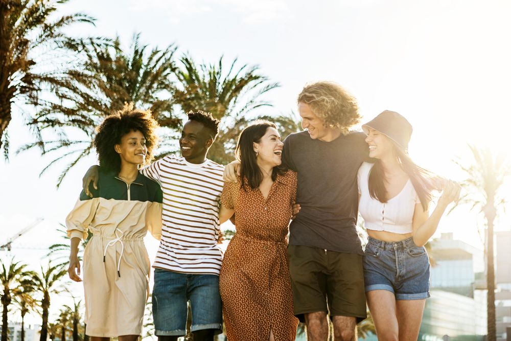 Group of friends walking together while laughing outdoors in summer