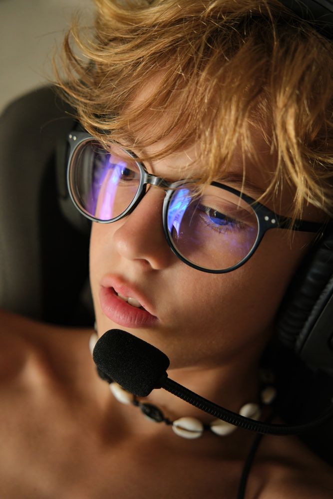 Crop young man in headphones and glasses sitting on a chair
