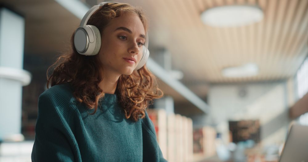 Serene Young Woman Engaged in Online Learning, Wearing Headphones and Focused on Laptop Screen