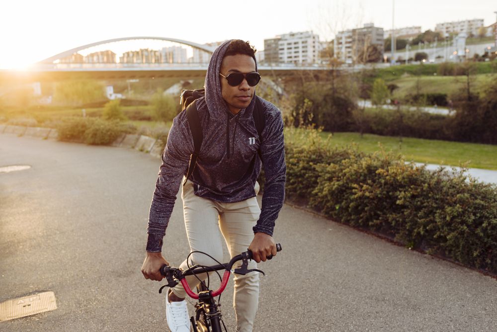 Young Black male riding bike near city bridge