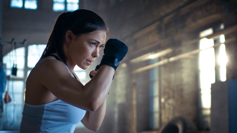 Athletic Woman is ready for Punch Punching Bag. She's Strong and Gorgeous Woman.