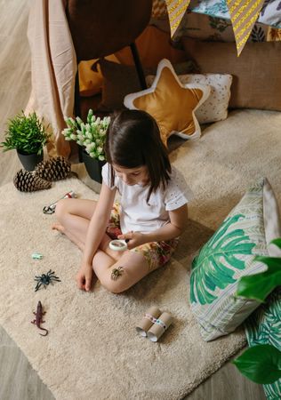 Girl playing observing toy bugs with a magnifying glass