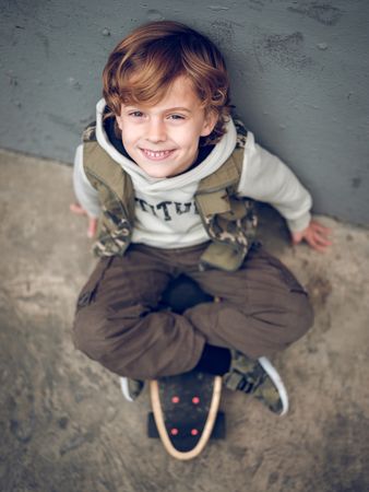 Smiling boy on skateboard on concrete ground