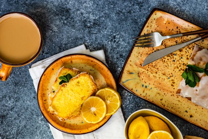 Top view of tasty lemon cake with fresh mint served on orange plates with tea