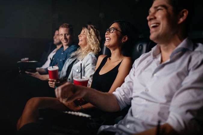 Group of friends laughing while watching a movie