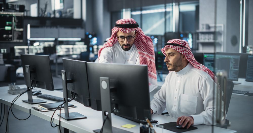 Young Team of Arab Specialists Working on Computers and Having a Conversation at a Workplace.