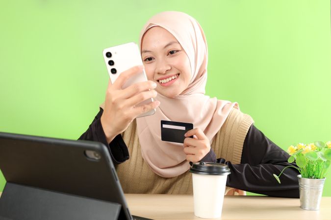 Young Asian Muslim Woman Wearing Hijab Headscarf Making Payment on Mobile