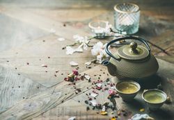 Golden teapot with little teacups on wood table
