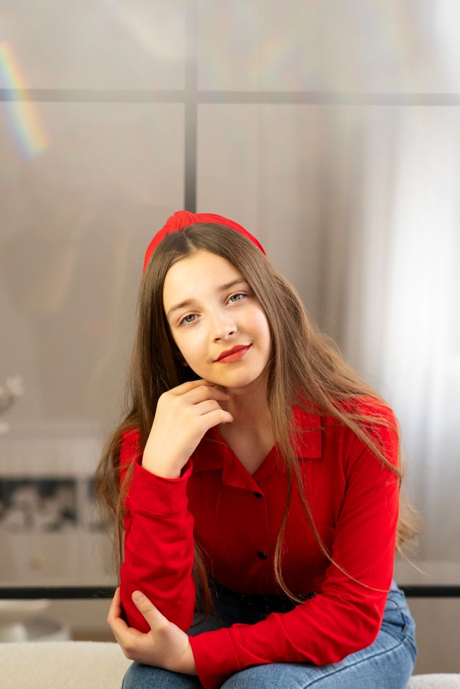 Portrait of teen girl in red shirt smiling gently.