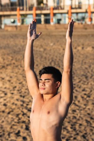 Asian man doing yoga pose on seashore