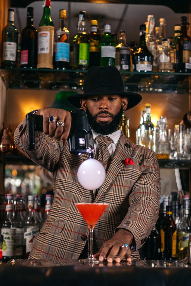 Stylish Black bartender preparing a cocktail with a smoke bubble in a traditional cocktail bar
