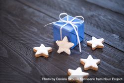 Gift wrapped in blue paper next to star shaped cookies 4Oom74