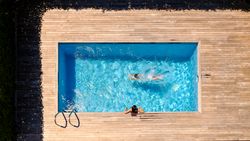 Anonymous people swimming in outdoor pool in yard
