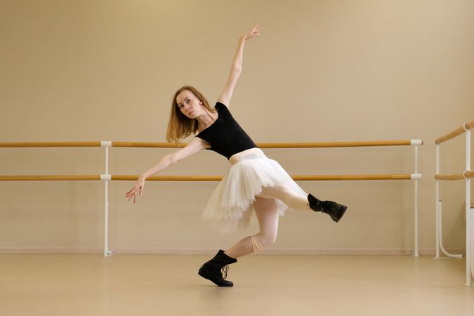 Ballerina in shoes and tutu, extending arm gracefully