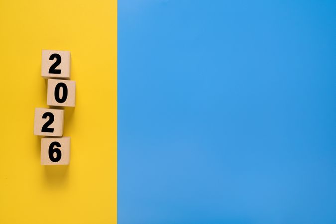 2026 text symbol on wooden blocks. isolated on blue and yellow background. copy space