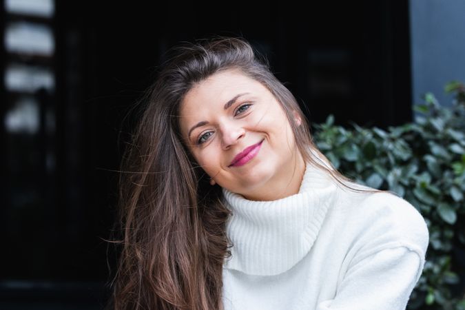 Happy stylish woman with white sweater resting in park