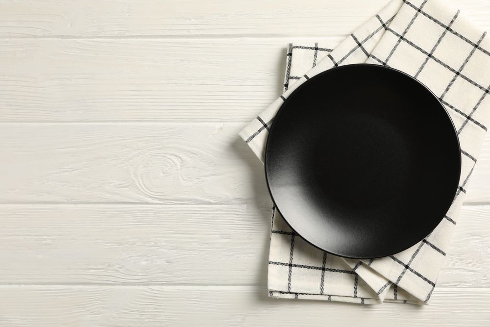 Kitchen towel with plate on wooden background, top view