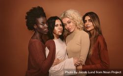 Group of beautiful female friends standing together on brown background 0LLEX0