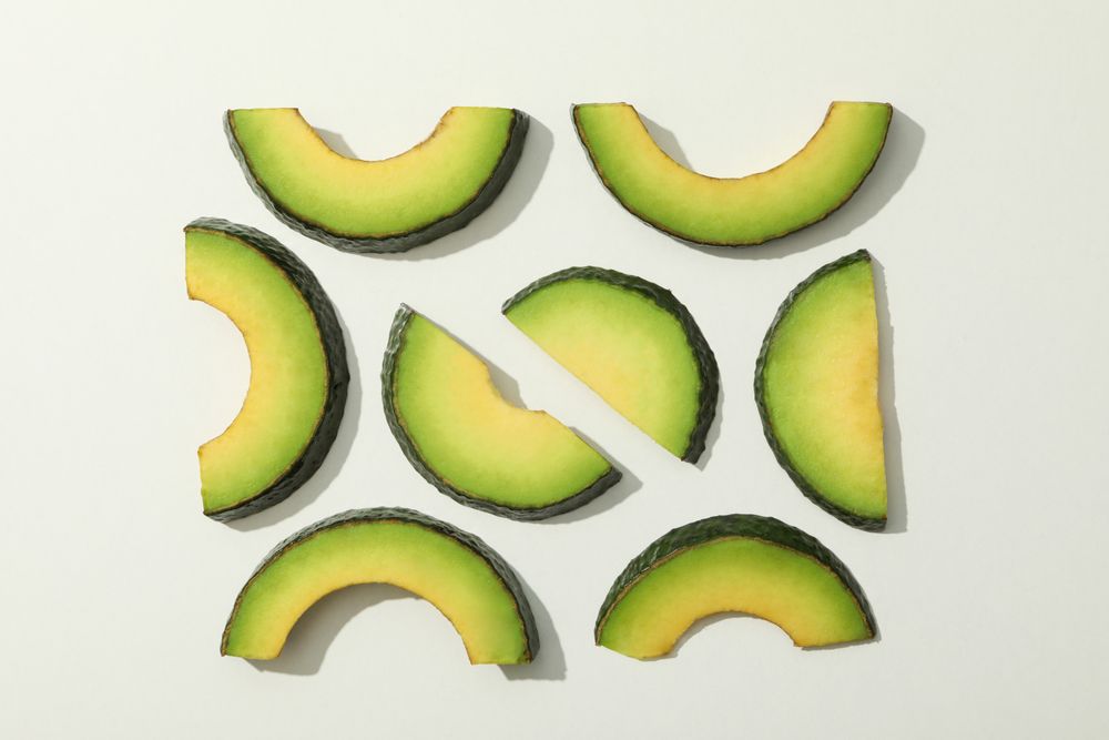 Fresh green avocado slices on blank background