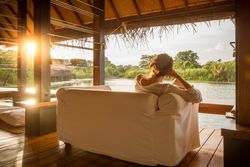 Woman sitting on couch and looking at calm lake