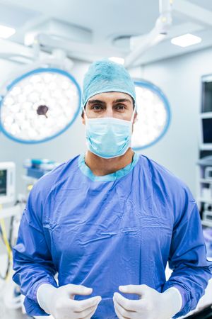 Portrait of surgeon wearing surgical gloves and scrubs in operation theater