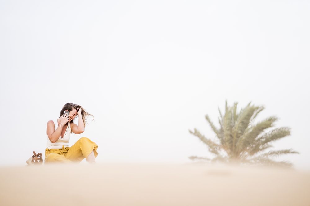 Happy woman using smartphone in desert