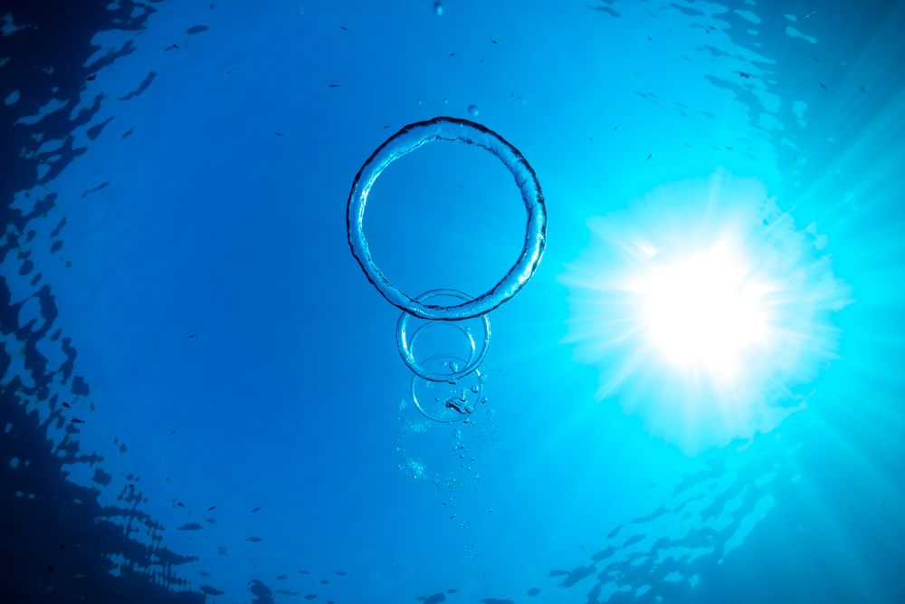 Toroidal bubbles under blue sea water in sunlight