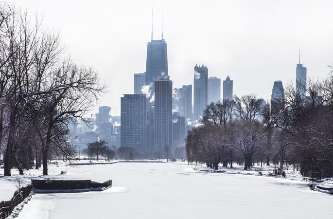 Snow covered park near city buildings