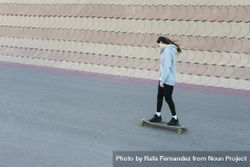Teenage girl skating on a longboard on road bxAvDd