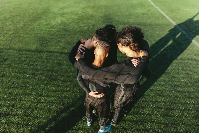 Group of athletic males standing in a huddle on soccer field