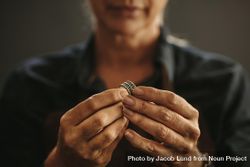 Close up of female jeweler hands examining ring at workshop bx7Wr4
