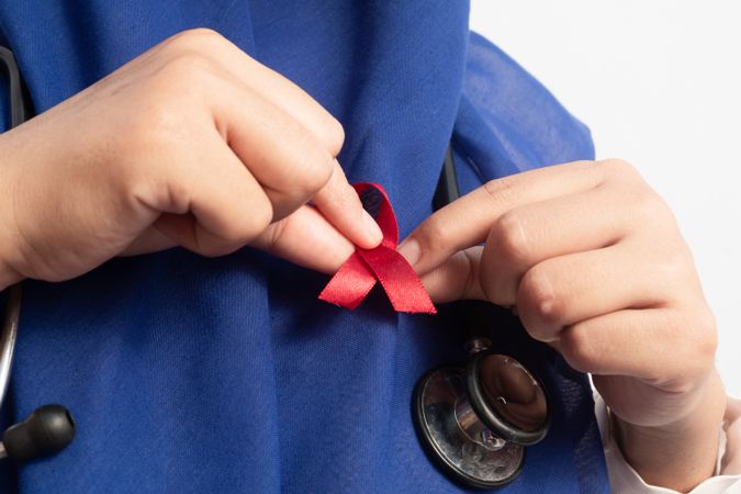 Close up Muslim Female Asian doctor or nurse wearing Red ribbons on cloth, HIV awareness concept, world AIDS day, world cancer day.