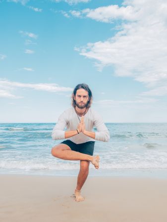 Man training yoga on beach