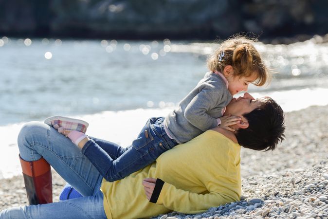 Mother lying on the beach with her daughter