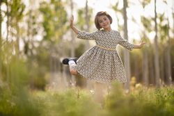 Girl standing in dress in nature surrounded by trees with open arms