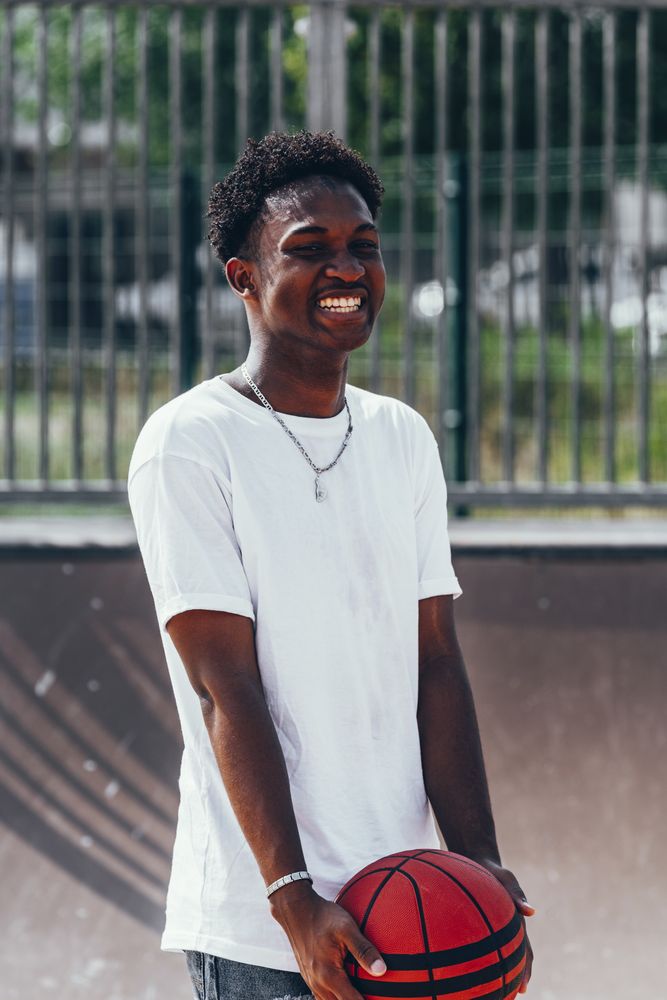 Black sportsmen with ball smiling and looking away