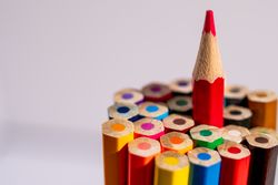 A red pencil is placed on top of a pile of pencils
