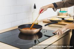 Person mixing sauce in pan on stove 5k3AL5