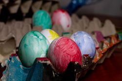 Set of painted Easter eggs in container on table