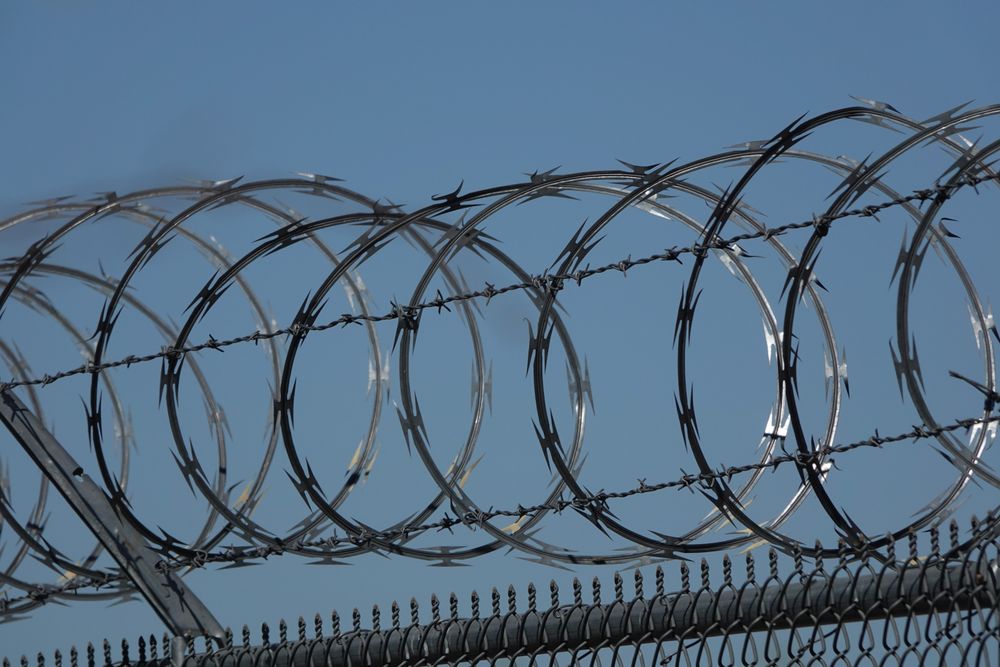 Barbed wire fence under blue sky
