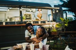 Happy Black couple hugging near food truck