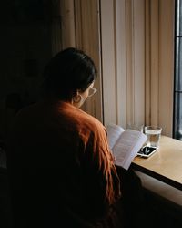 Back view of woman in brown shirt reading book bEJGN0