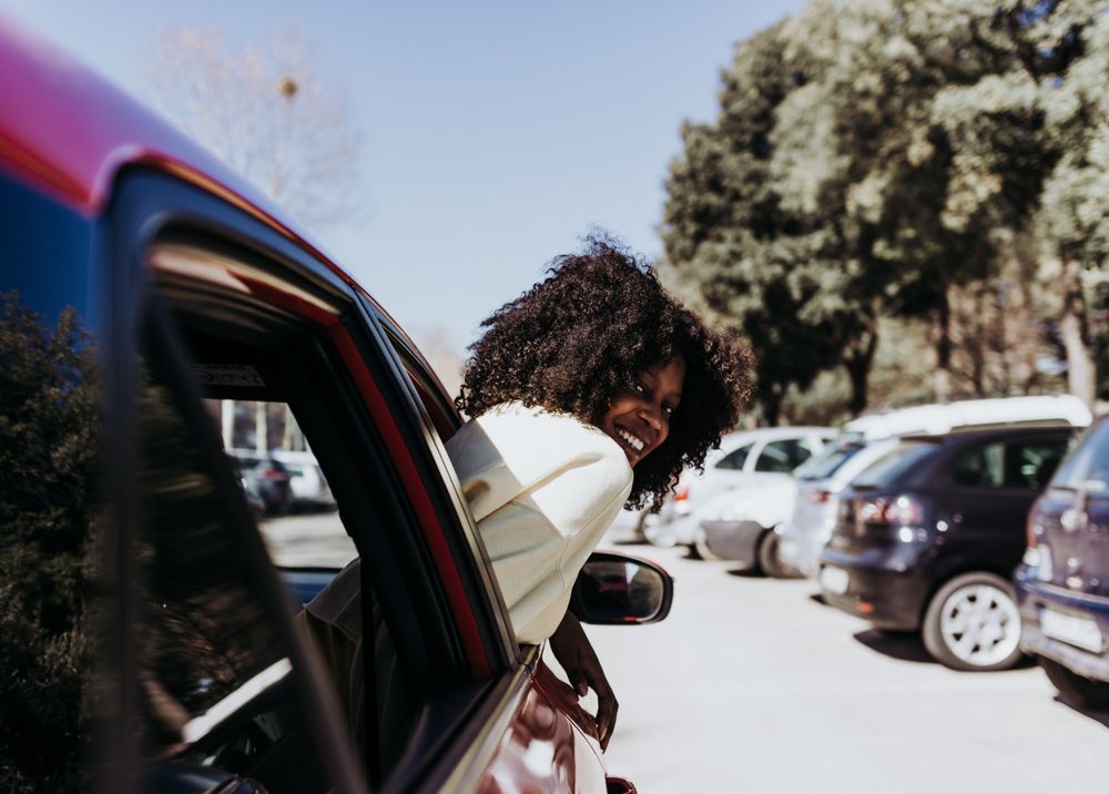 Black woman with afro hair peeking out of the car .