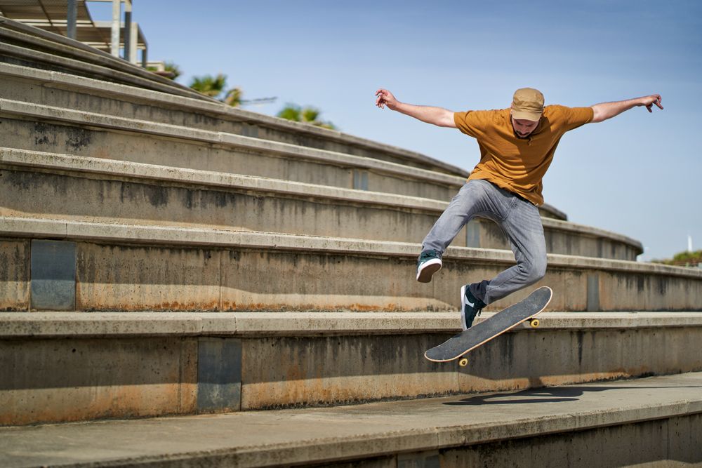 A young man doing an ollie 360 flip with his skateboard on some bleachers