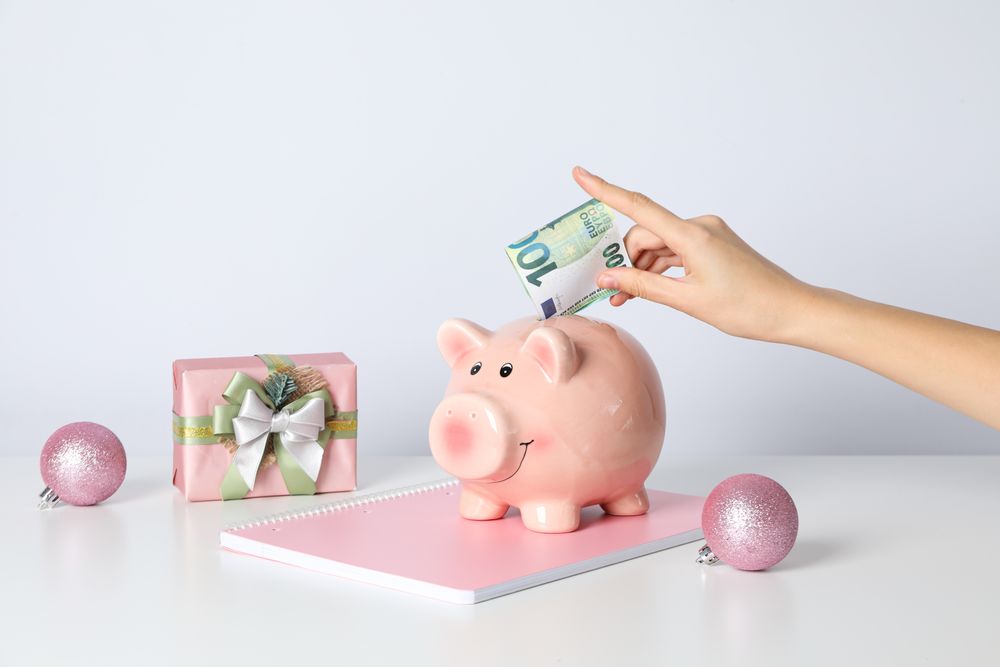 Piggy bank, female hand with cash and gift box on blank background