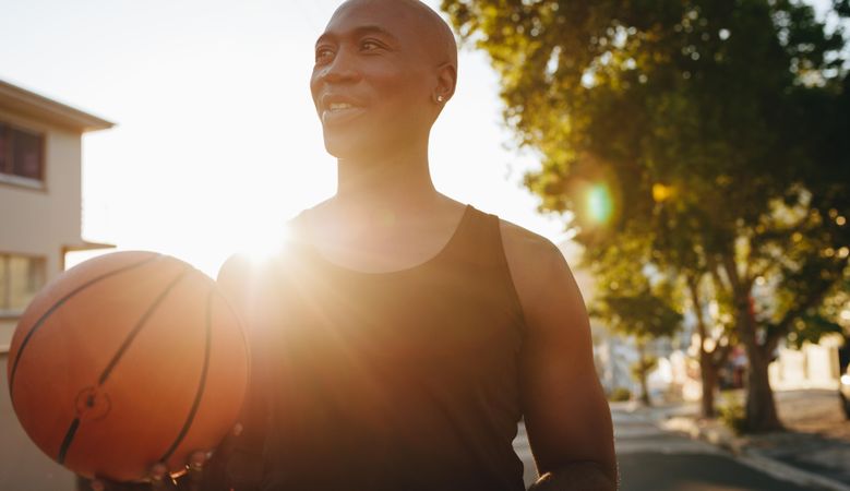 Man holding basketball with sunflare